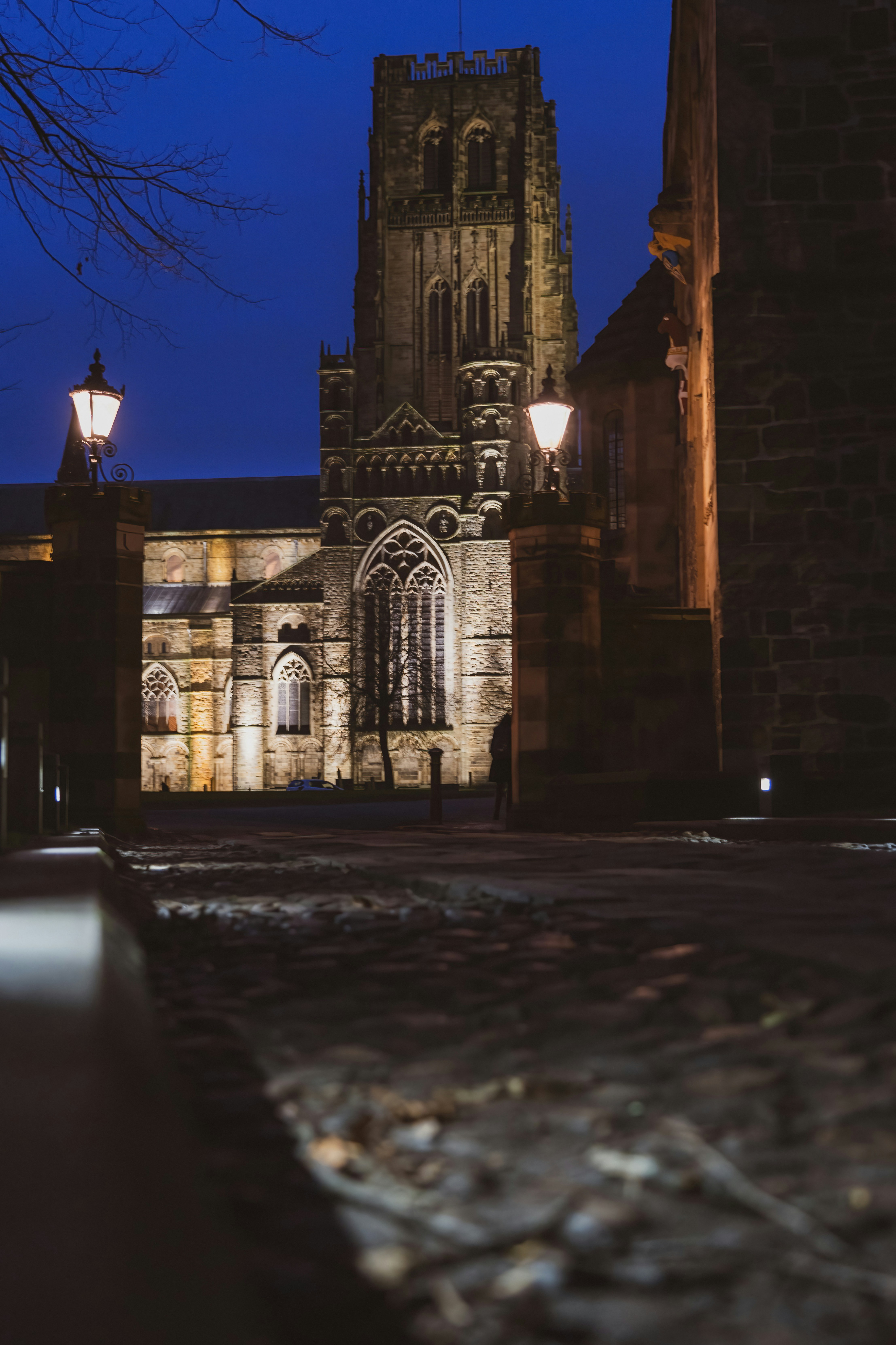 Durham Cathedral illuminated at dusk beside cobbled streets in Durham city centre